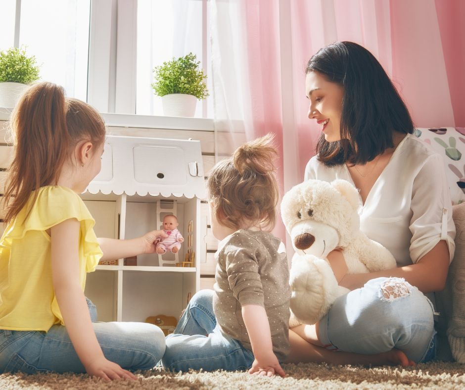 mama bawiąca się z dziećmi w odgrywanie ról przy domku dla lalek